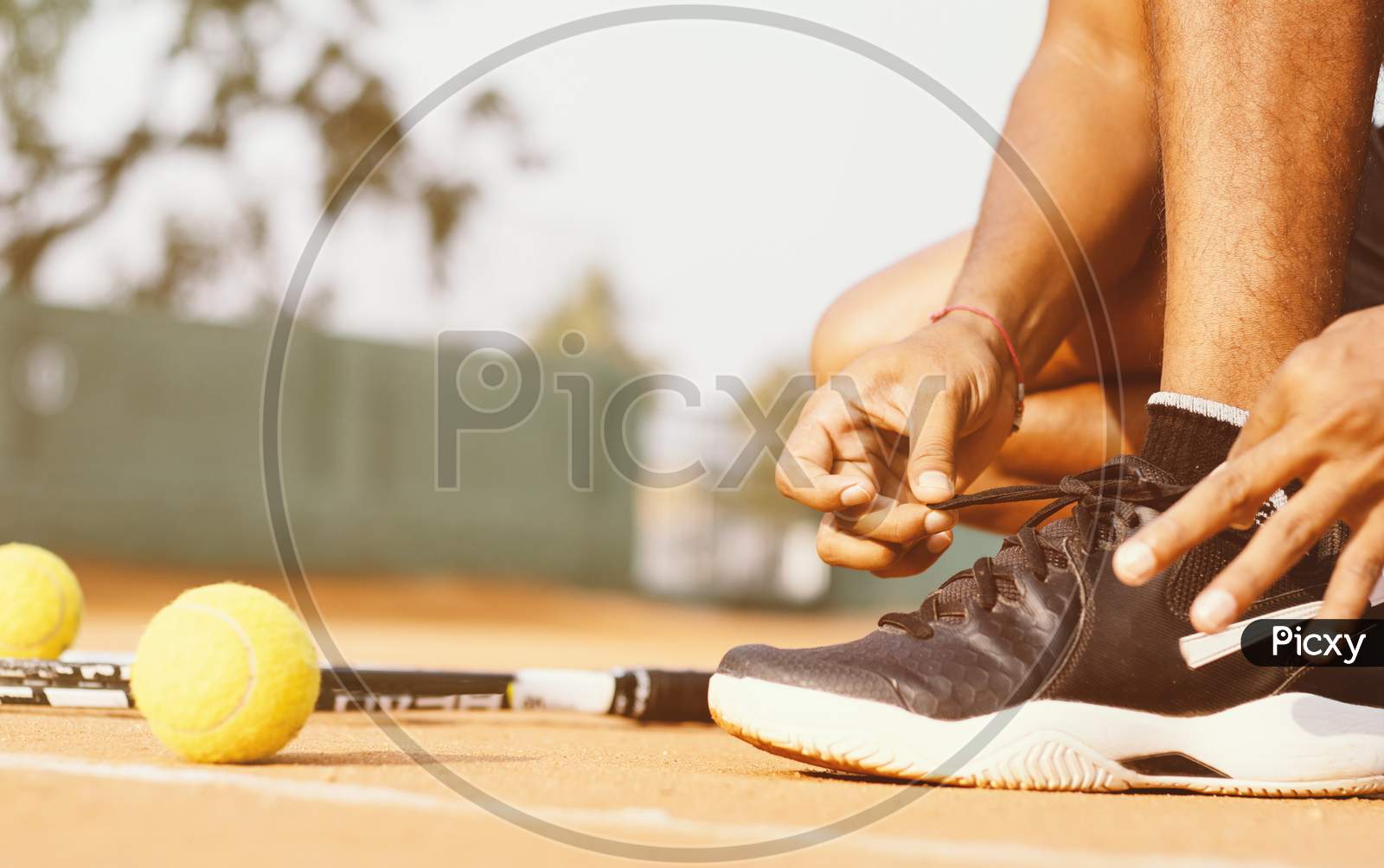 Close up shot of a  Young Indian Man tying Shoelace in a Tennis Court