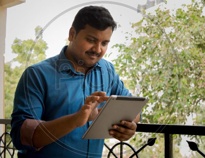 A Young Indian Man Using Tablet Gadget or iPad