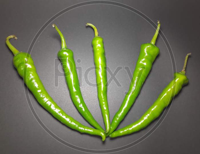 Five Fresh Green Chillis On A Black Background. Clipping Path Included.
