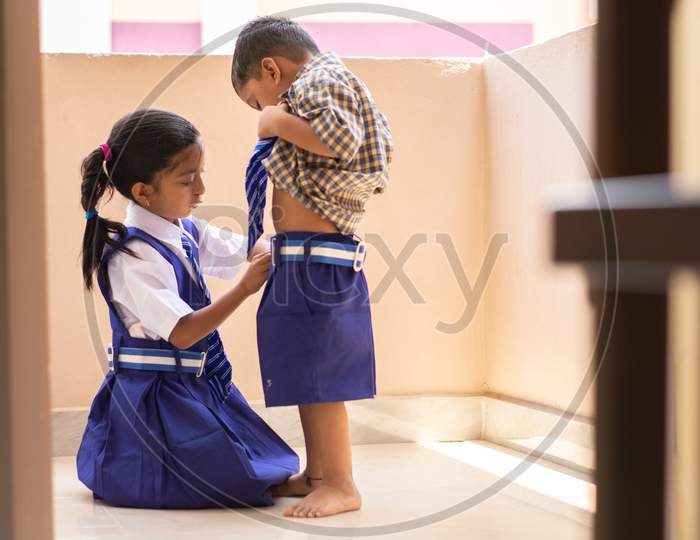 A sister Helping her brother to wear School Dress
