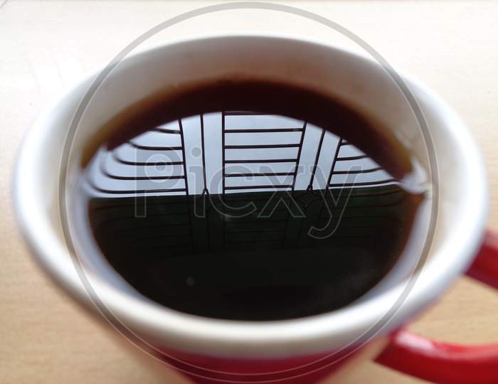 A cup of tea reflecting sky through window