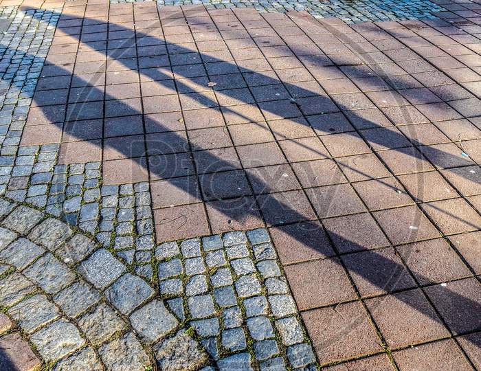 Shadows Of People In A European Shopping Area On A Cobblestone Ground