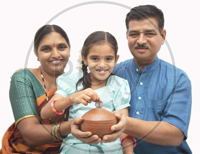 A Happy Three membered Indian family with a kid holding money saving pot isolated with White Background