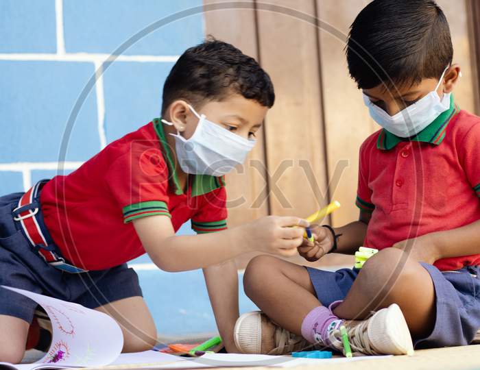Kids Busy In Writing With Medical Face Mask Wearing Due To Covid-19 Or Coronavirus Outbreak Or Pandemic At School