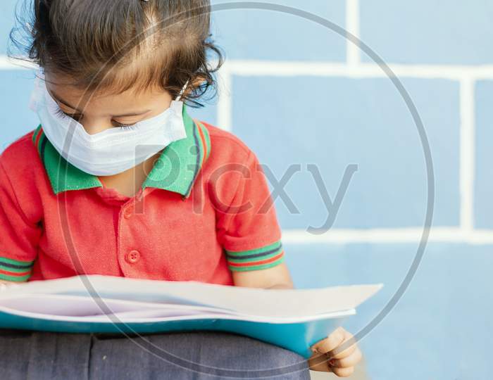 Covid 19 Or Coronavirus And Air Pollution Pm2.5 Concept - Little Girl Wearing Medical Mask And Busy In Writing At School - Showing Wuhan Covid-19 Or Sars Cov 19 Outbreak Or Epidemic Of Virus.