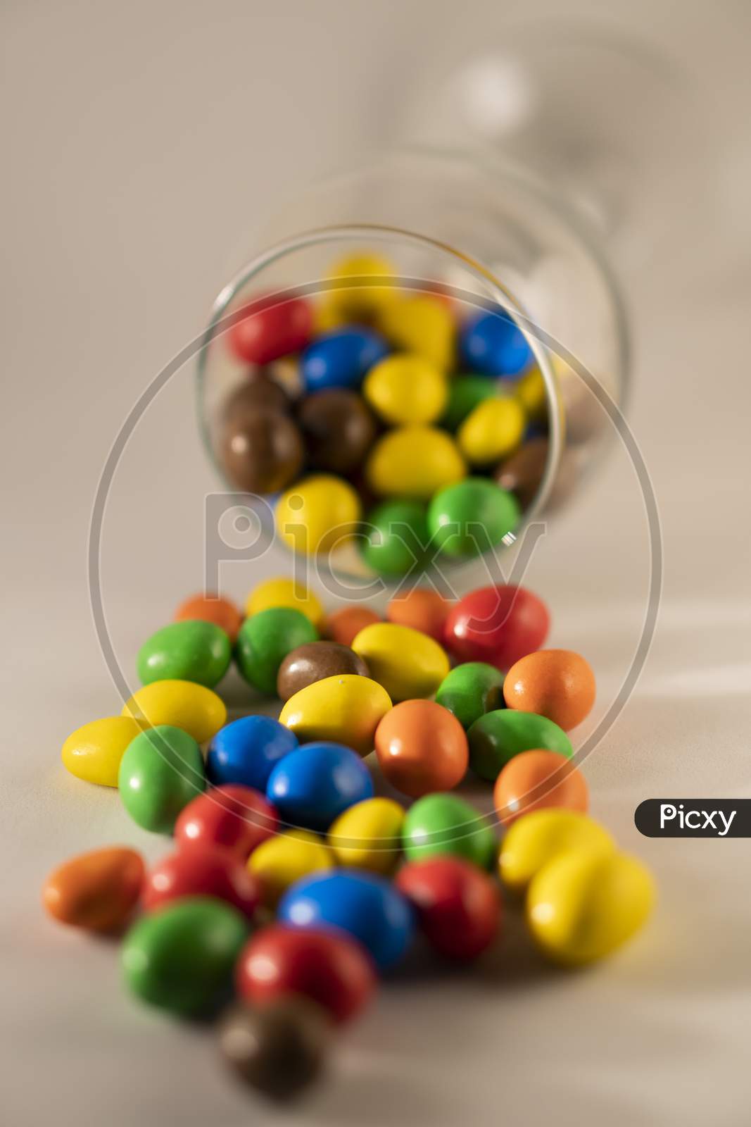 Multi color chocolate candy or candy balls scattered on a multicolored background.