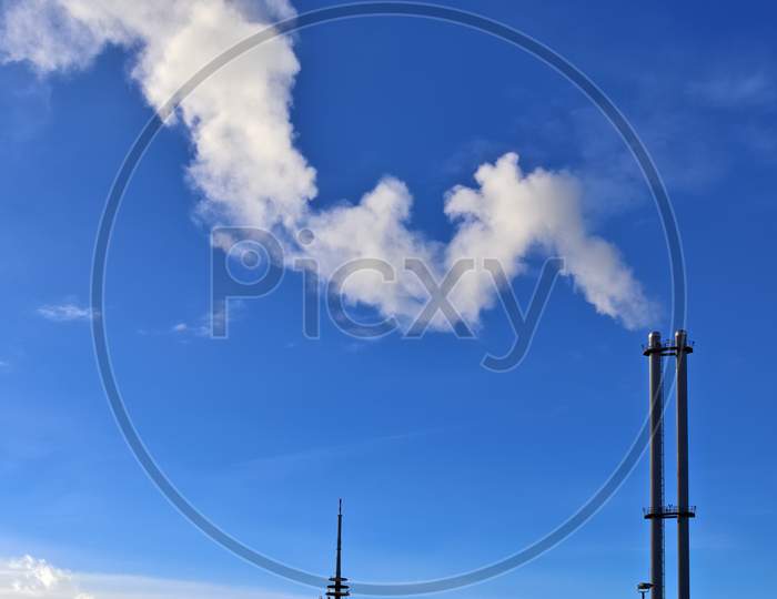 Industry Pollution From Factory Smoestacks In A Deep Blue Sky