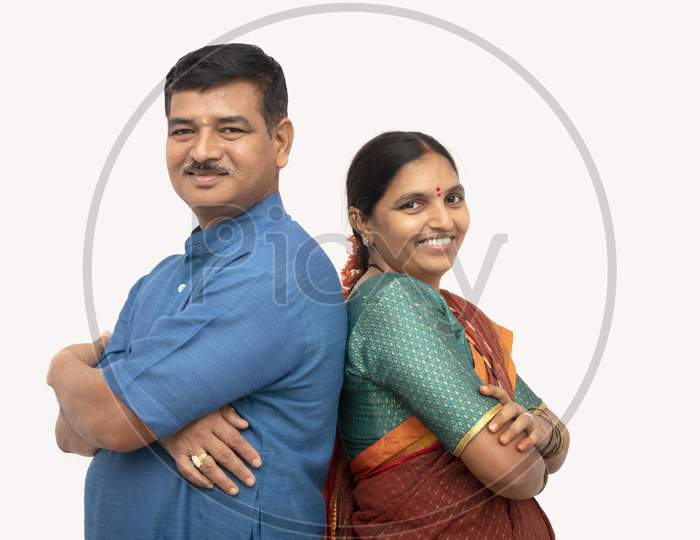 Happy Indian Couples In Traditional Dress With Arms Crossed Standing Back To Back On Isolated Background - Concept Of Happy And Cheerful Couple Relationship.