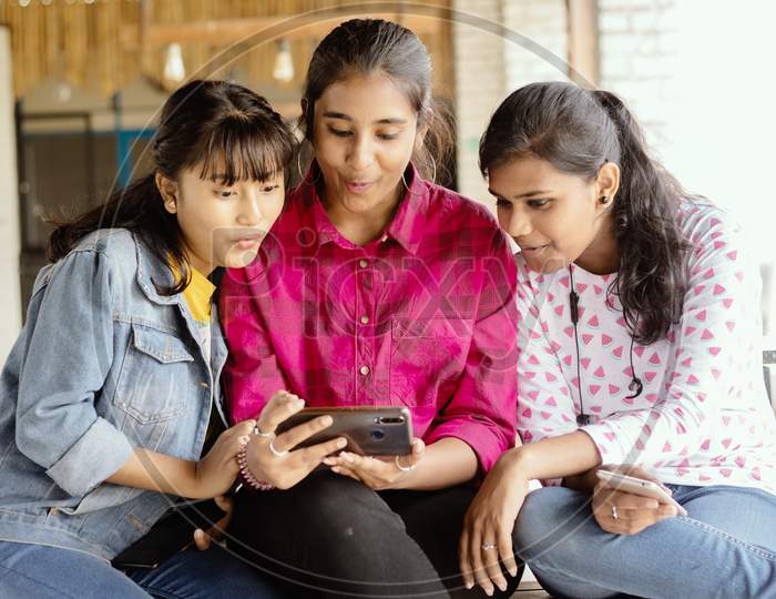 A Group of Happy Young Girls  using Mobile Phone or Smartphone At Outdoors