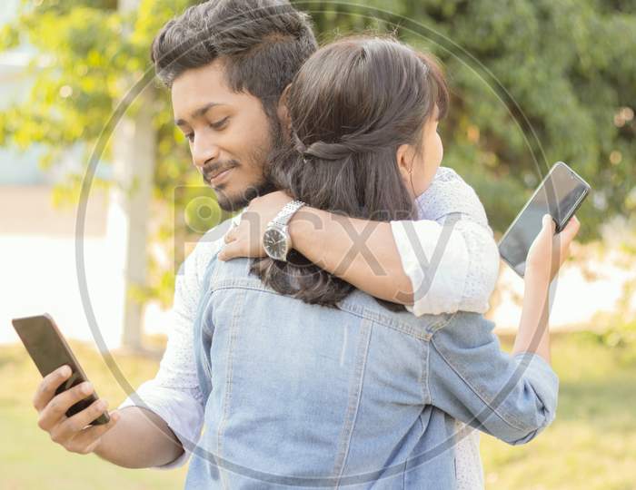 A Couple in Hugged pose using a Smartphone