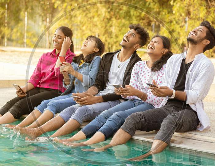 A Group of Happy Young People Talking to each other and Laughing Loudly At Outdoors in a Pool