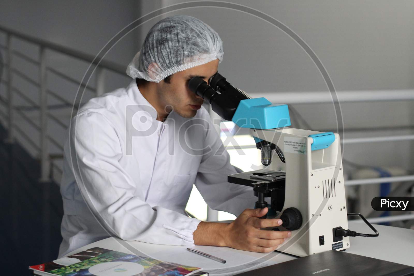 A SCIENTIST IS RESEARCHING WITH MICROSCOPE TO FIND A MEDICINE.