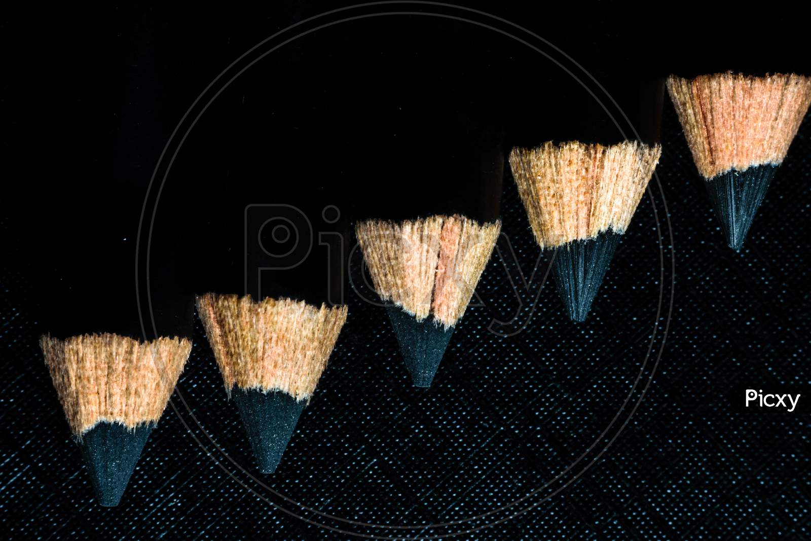 A Group Of Pencils Are Kept On A Dark Paper In Ascending Order. Top View