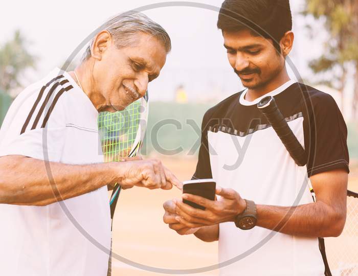 A Young and Old Tennis Player using Smartphone in Tennis Court
