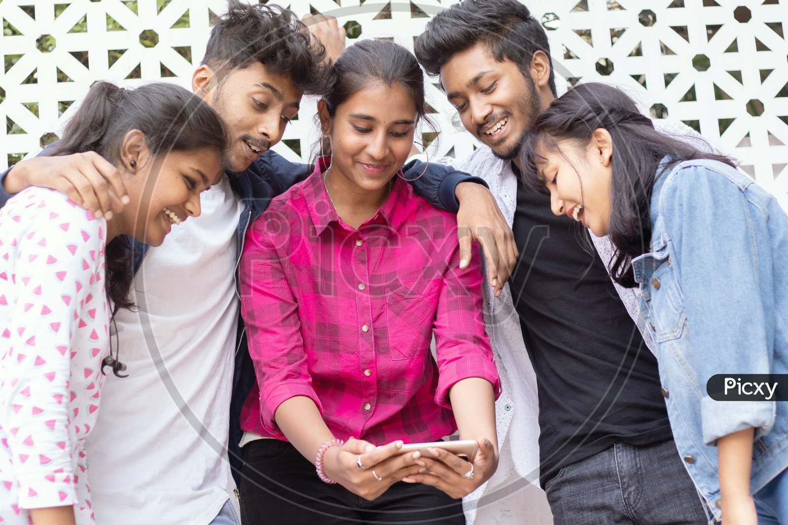 A Group of Happy Young People using a Mobile Phone or Smartphone At Outdoors