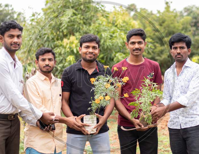 Group of Young People Posing towards the Camera with Plants in Hands