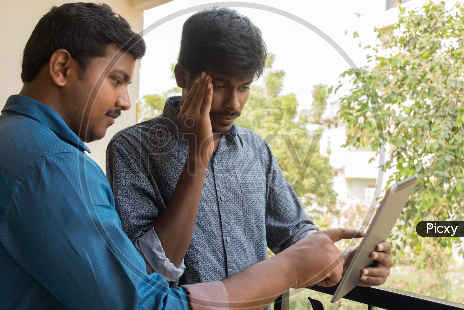 A Couple Of Worried Young Indian Men's Using a Tablet Gadget