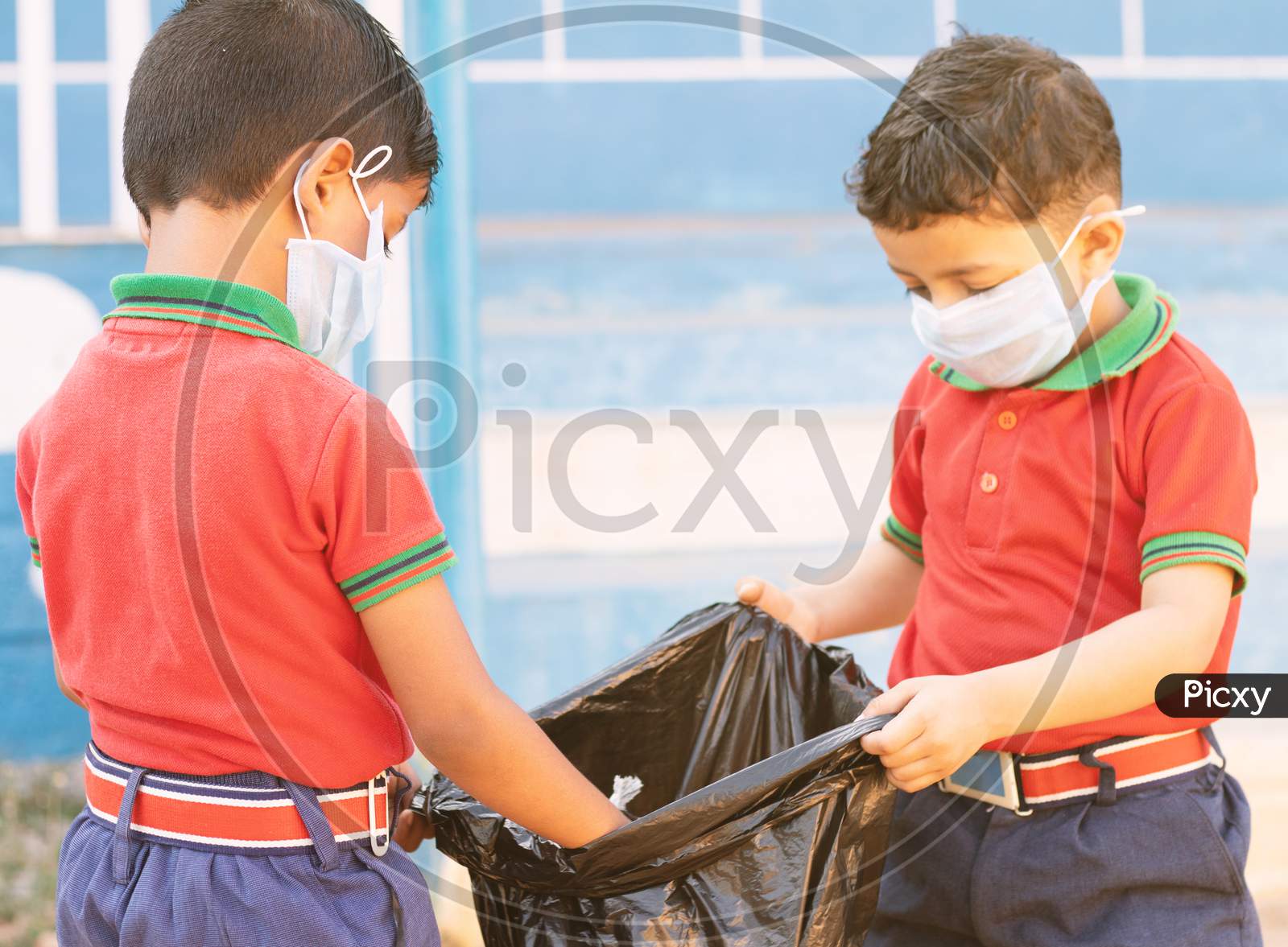 A couple of Kindergarten Kids collecting Garbage into a Garbage Bag