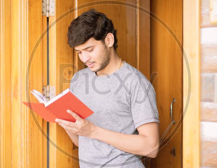 Young Indian Man Reading Book at Home