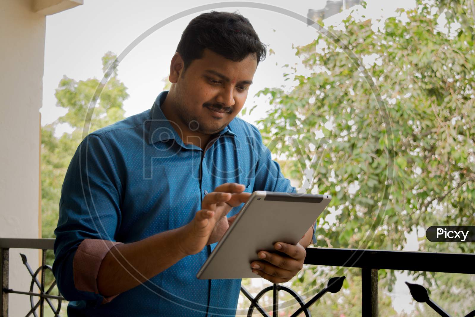 A Young Indian Man Using Tablet Gadget or iPad