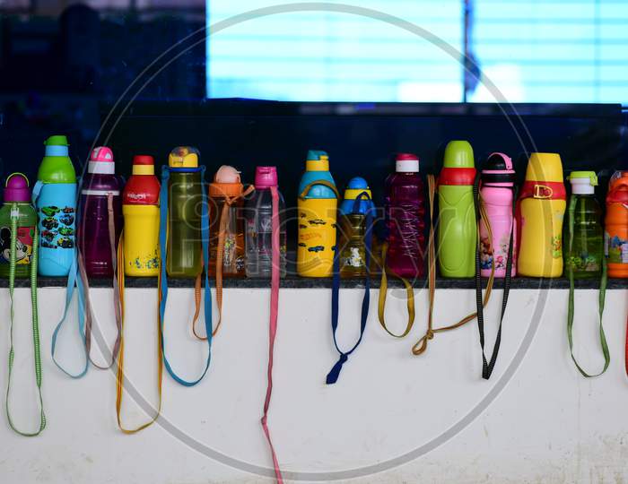 Water bottles of students lined on a wall out of the class