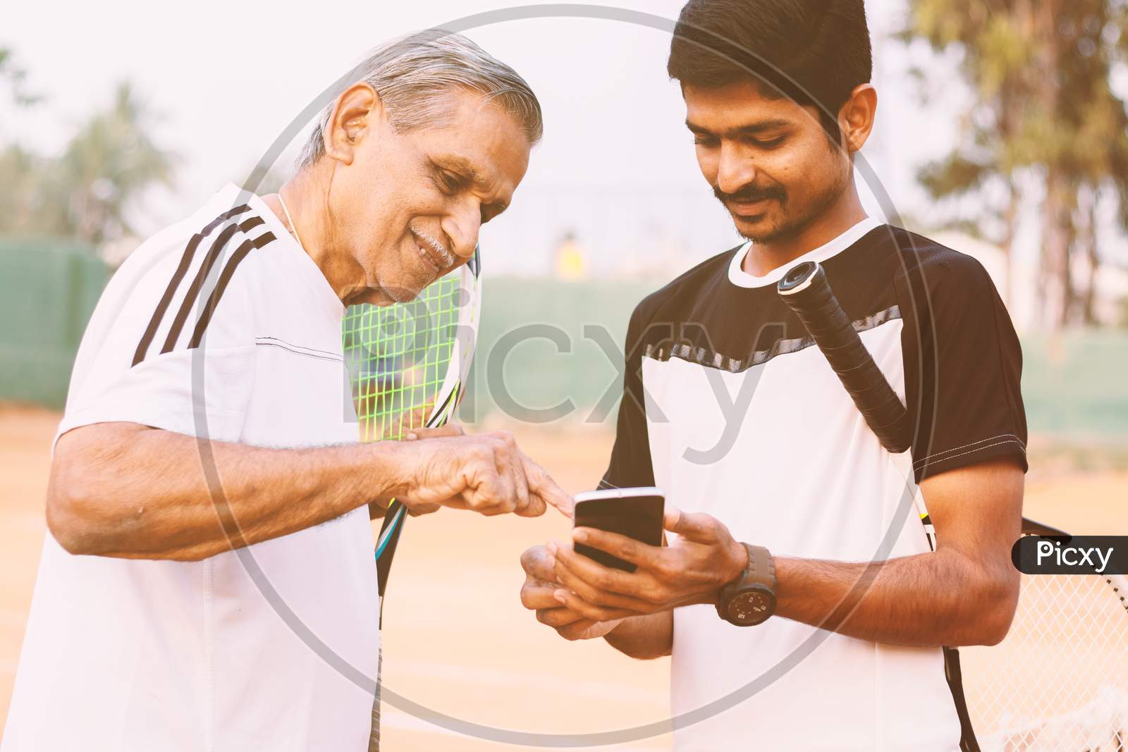 A Young and Old Tennis Player using Smartphone in Tennis Court