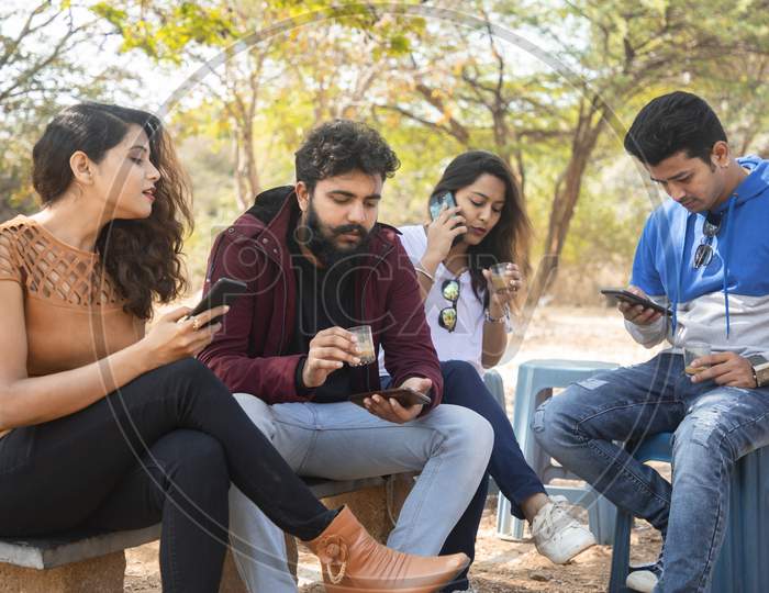 A Group of Happy Young People using Mobile Phone or Smartphone At Outdoors
