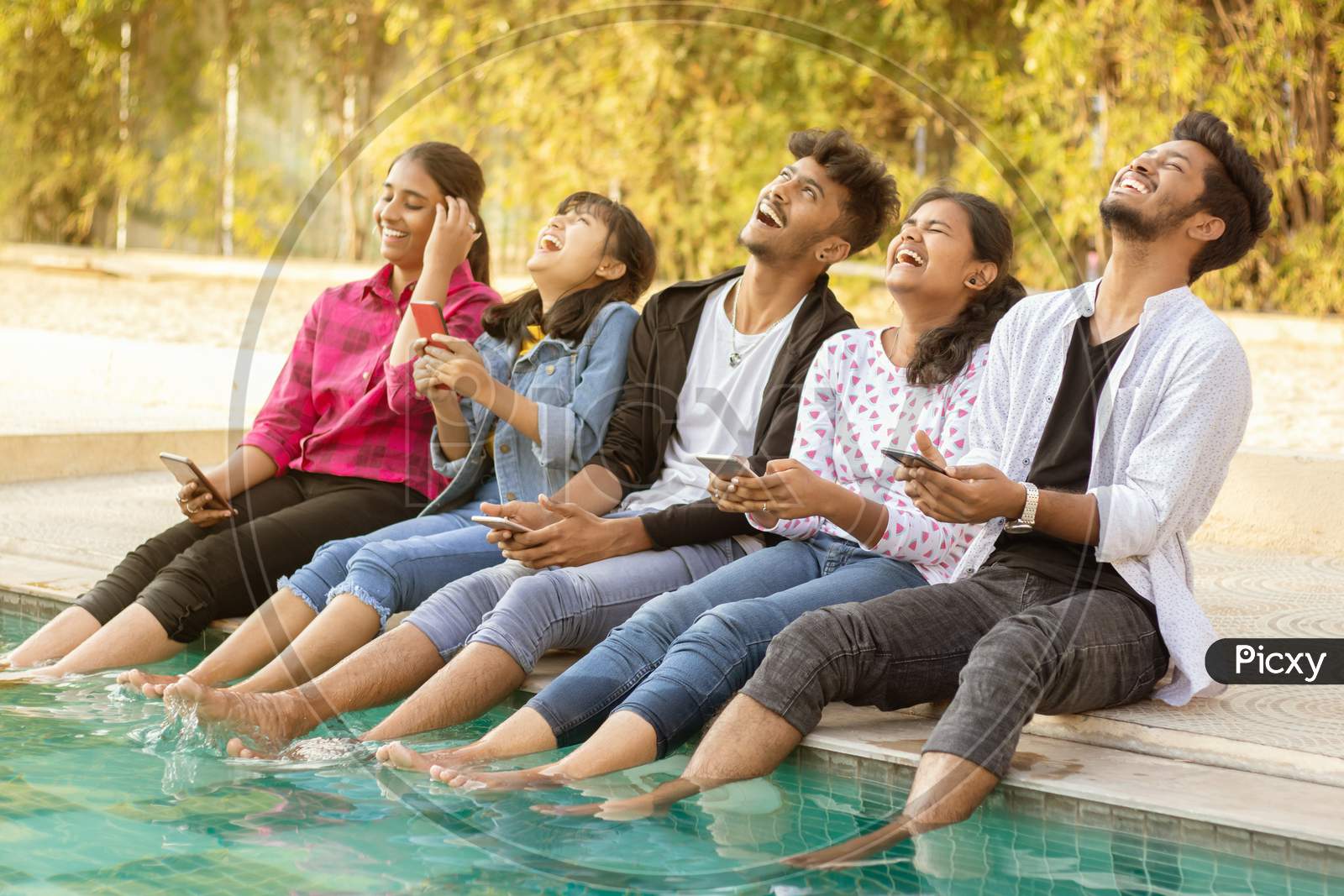 A Group of Happy Young People Talking to each other and Laughing Loudly At Outdoors in a Pool