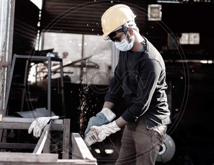 A Young Welder doing welding with a Helmet and Mask during Corona Virus Pandemic