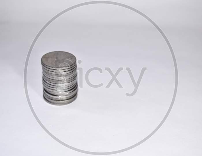 Coins Stacked On Each Other On White Background. Copy Space Available. Selective Focus Image.