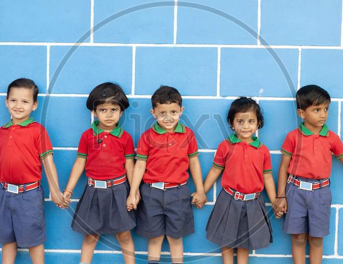 A Group of Kindergarten Kids Standing Along the side of a Wall