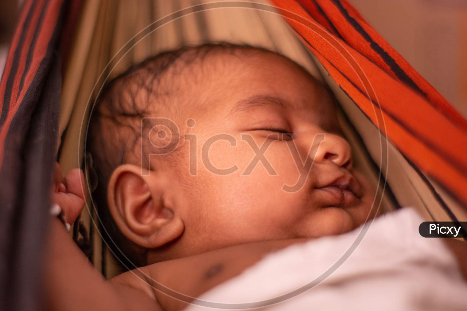 Closeup Of Cute Little New Born Baby Sleeping In Cradle Made Of Saree In India