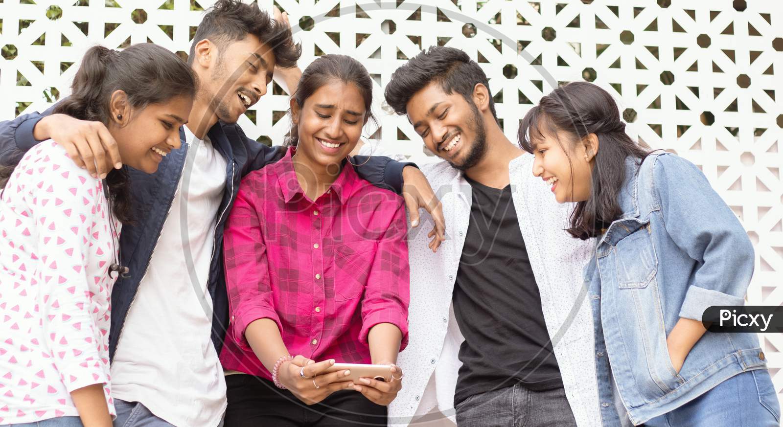 A Group of Happy Young People using a Mobile Phone or Smartphone At Outdoors