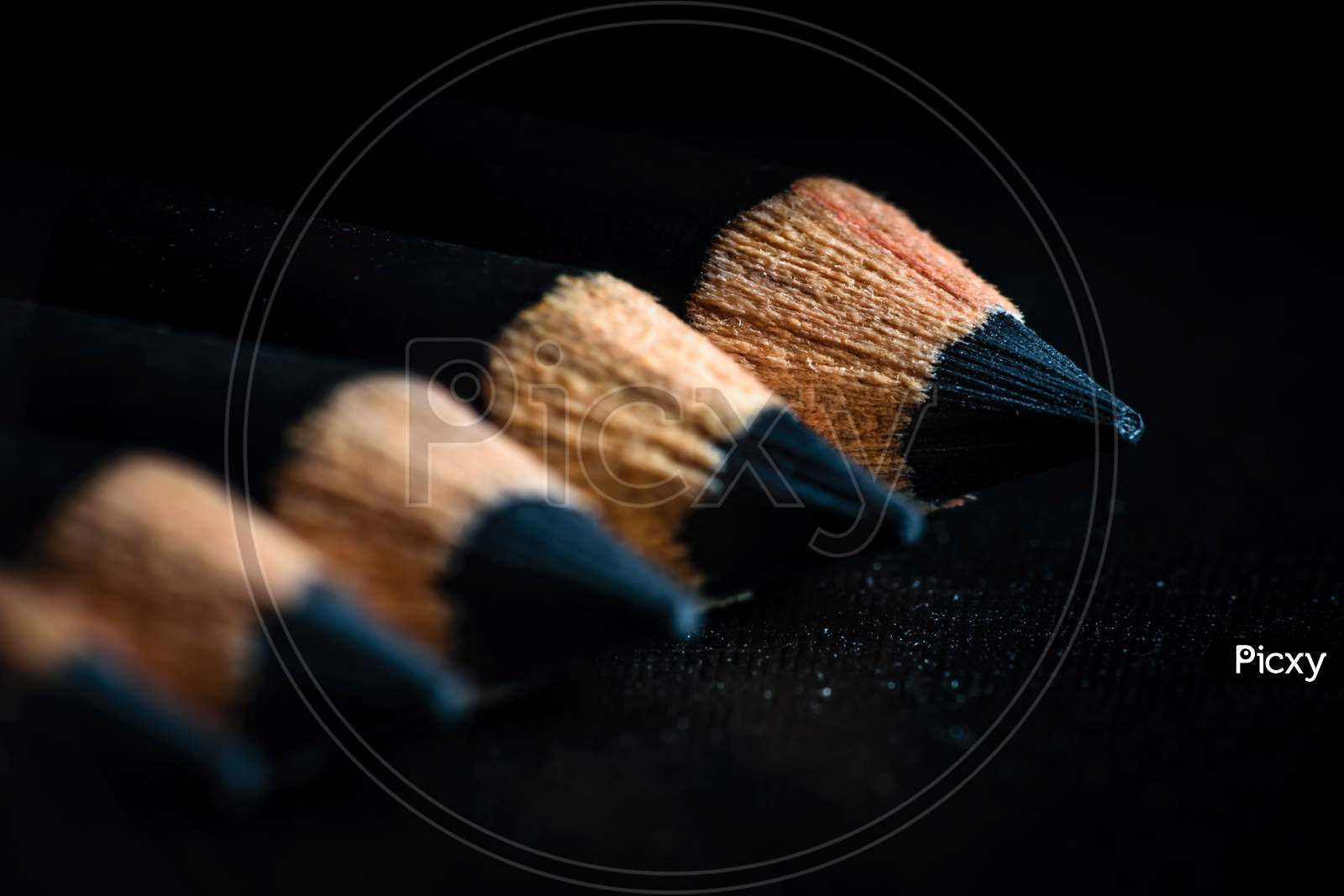 A Group Of Pencils Are Kept On A Dark Paper In Ascending Order. Selective Focus On The Tip Of The Distal Pencil