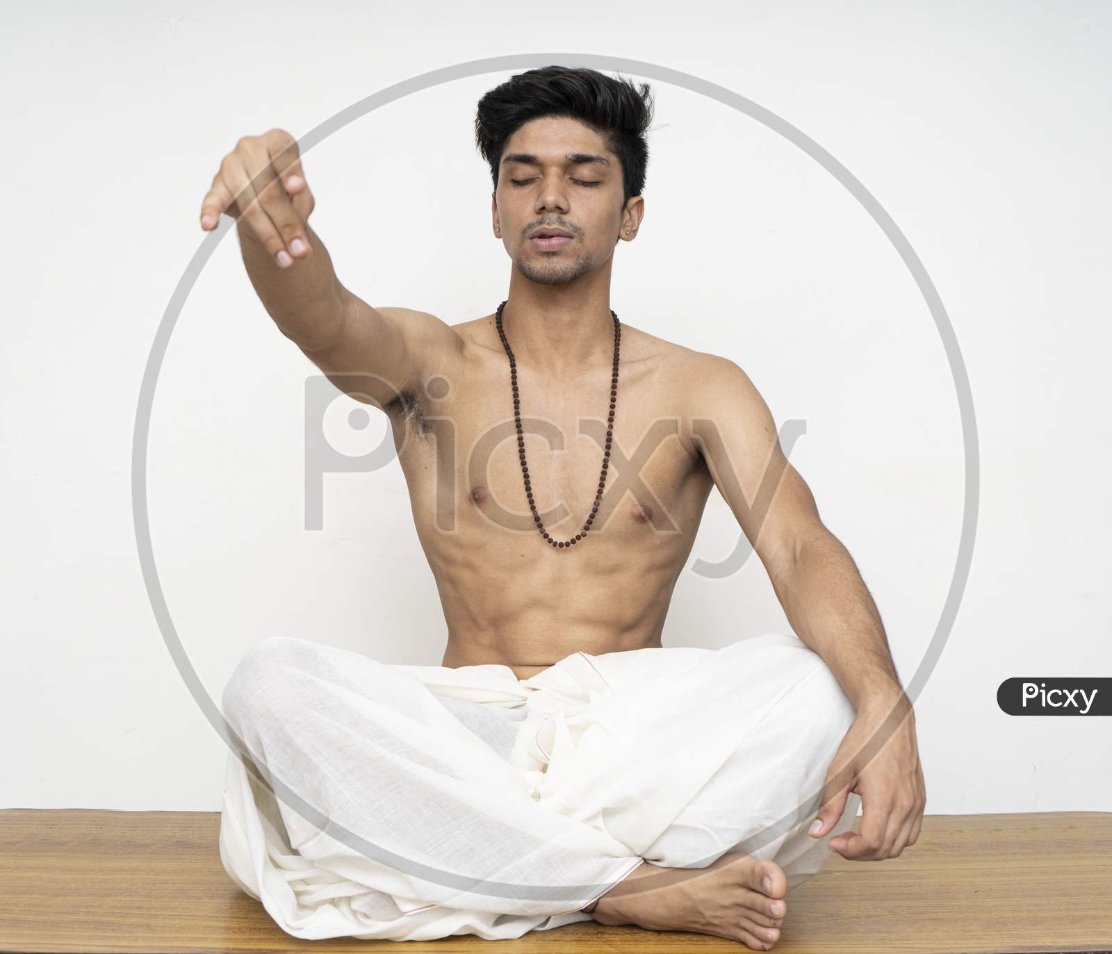 Young Indian Priest Sitting In Dhoti, Wearing Rudraksh, Showing Up His Hand Representing Giving Should Be The Human Nature.