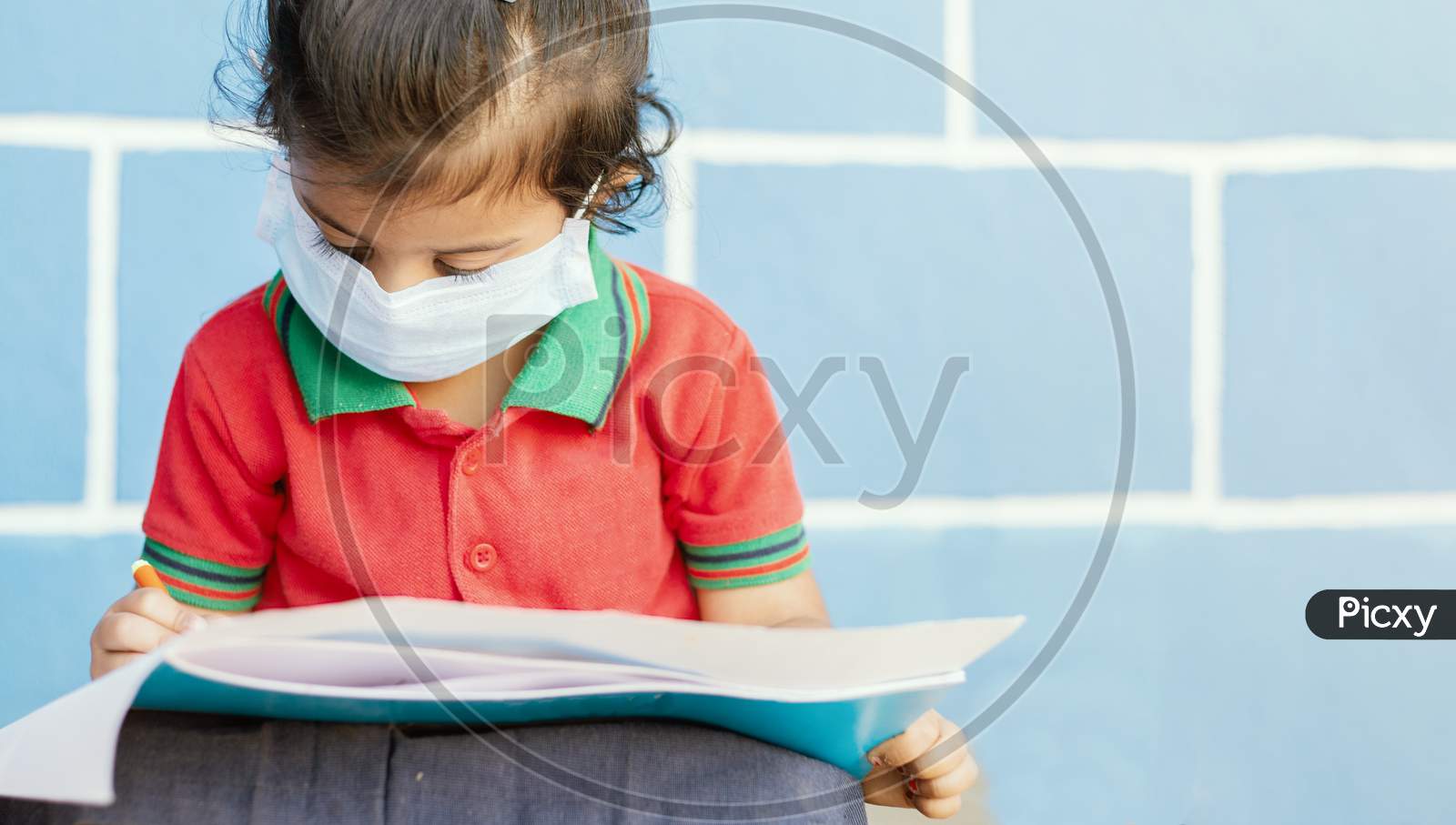 Covid 19 Or Coronavirus And Air Pollution Pm2.5 Concept - Little Girl Wearing Medical Mask And Busy In Writing At School - Showing Wuhan Covid-19 Or Sars Cov 19 Outbreak Or Epidemic Of Virus.