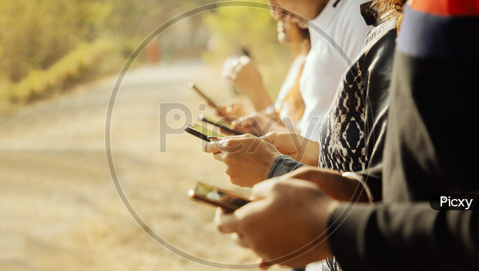 A Group of Happy Young People Using a Mobile Phone or Smartphone At Outdoors