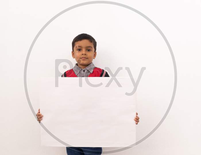 Concept Of Child Protest Showing With Young Boy Holding Large White Placard On Isolated Background.