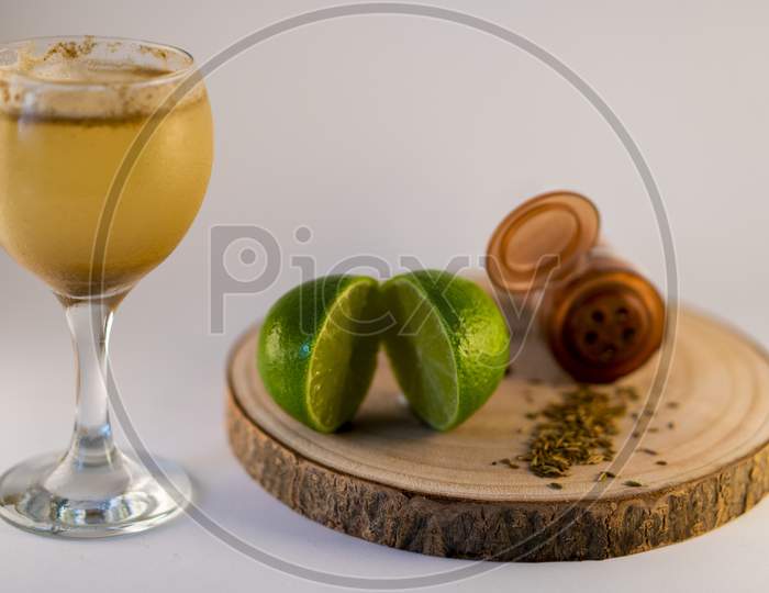Glass of fresh summer cocktail or mocktail with lemon and herbs garnishing on a white background.