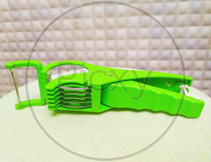 Plastic green colour Multi Vegetable Cutter for kitchen uses isolated on white surface and in blurred background. selective focus on subject