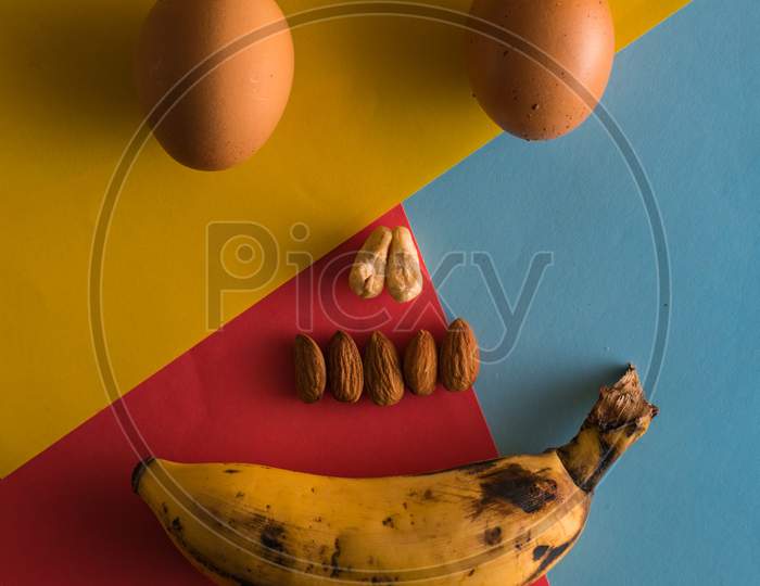 Egg Banana And Some Nuts Make Smiley Face On Colorful Background