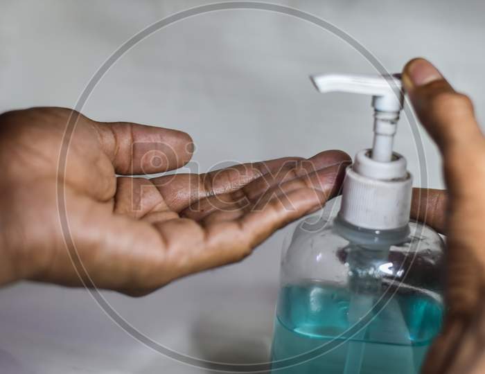 indian man cleaning a hand with hand sanitizer on a white background, Hand Snitizer