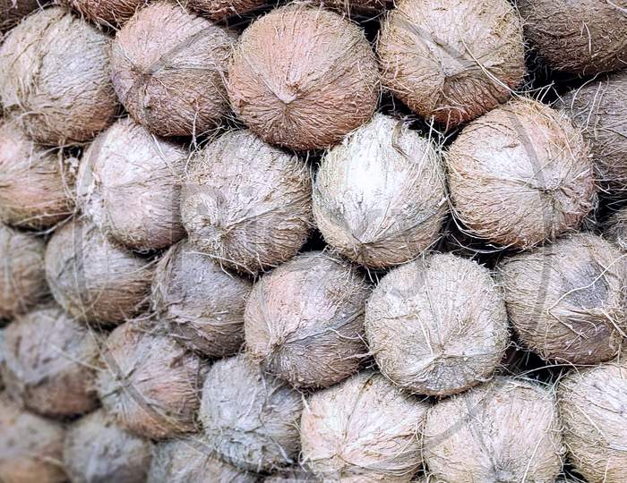 Stack Of Mature Dehusked Coconuts Kept In Market For Sale. Top 3D View. Perfect For Wallpaper And Background.
