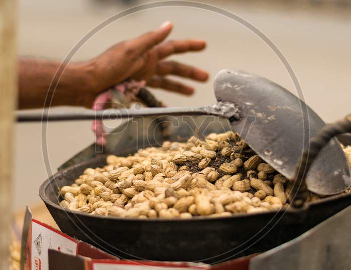 Peanuts Are Roasting Using Dry Sand On A Big Pan With A Big Spoon In Road Side