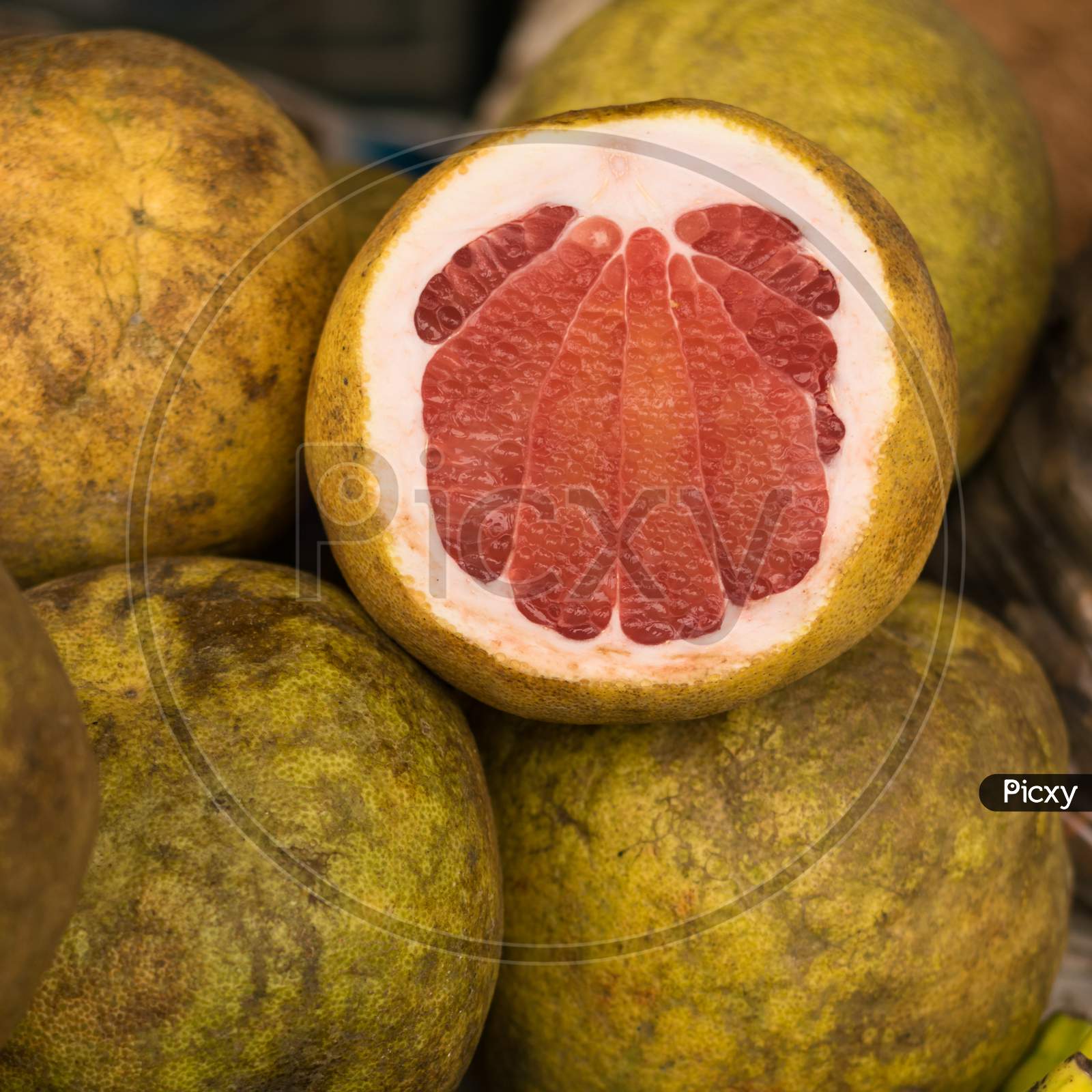 Ripped Pomelo Fruit Displayed In A Local Fruit Shop. One Is Peeled From The Front Side