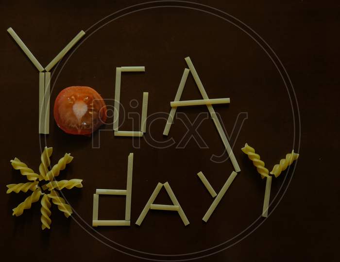 Yoga day text with spaghetti and tomato on a dark background