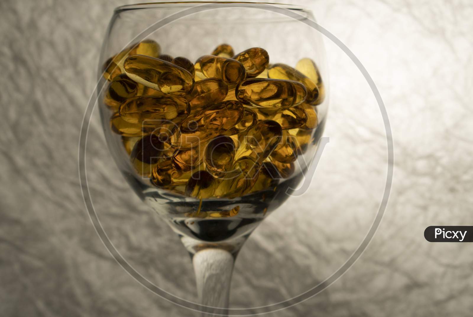Omega-3 capsules in a glass on a white background.