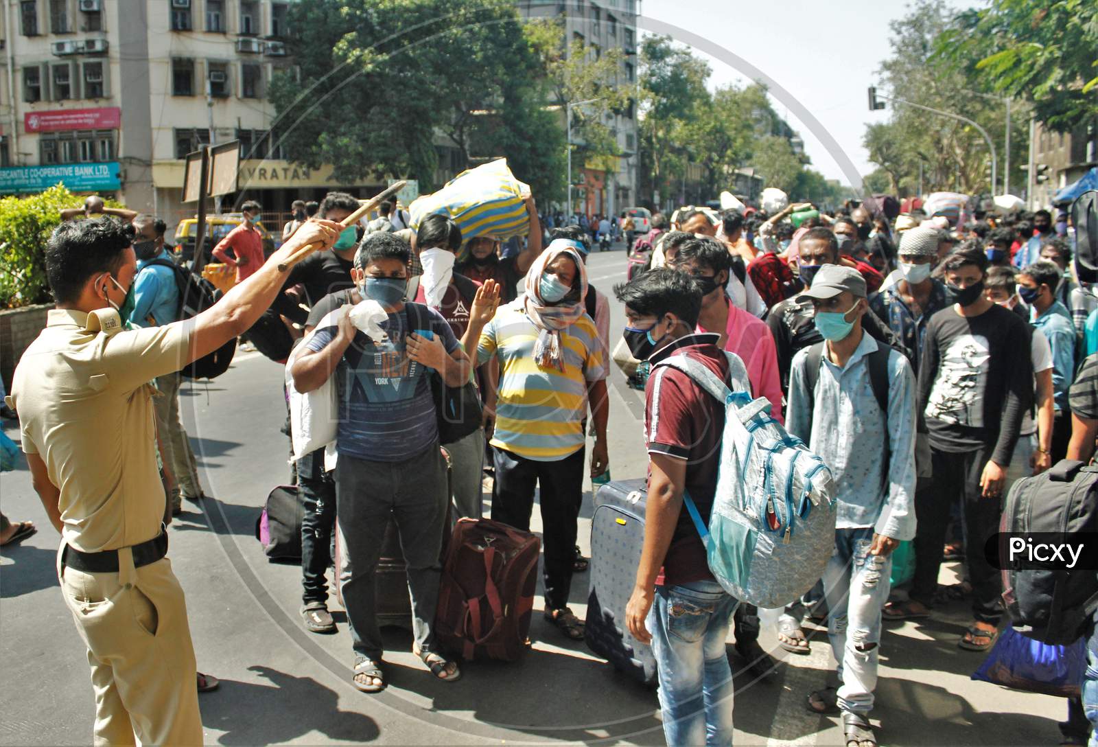 A policeman instructs the migrants to form a proper queue and not gather in huge numbers, who are waiting to go to CSMT,  that will take them to their home state during an extended lockdown to slow the spreading of the coronavirus disease (COVID-19), in Mumbai, India, May 30, 2020.