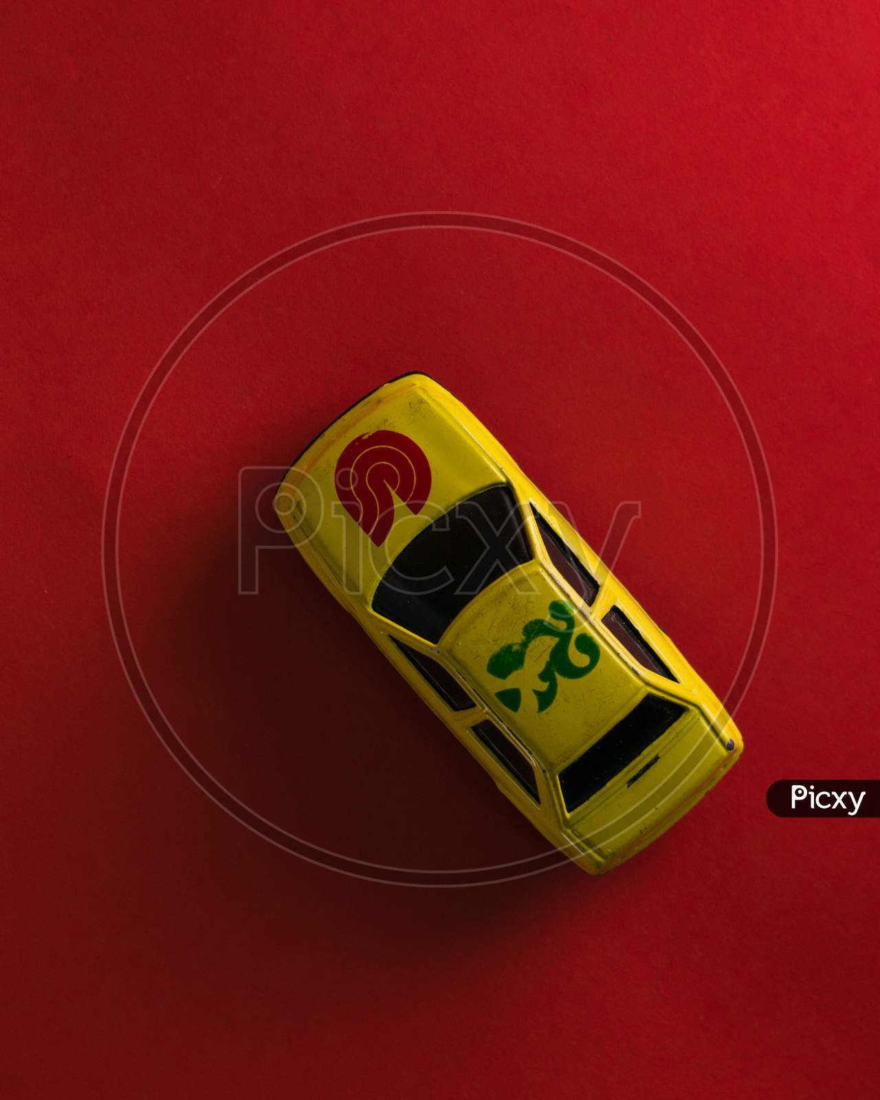 A mini yellow colour toy car on a red background