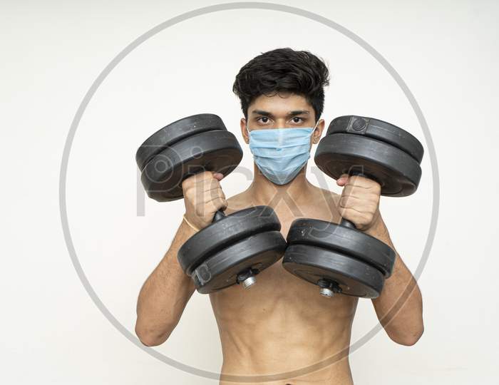 Fitness Man With Mask For Epidemic Protection Working Exercise For Arm,Biceps, And Shoulders With Dumbbells.Training In Epidemic Time